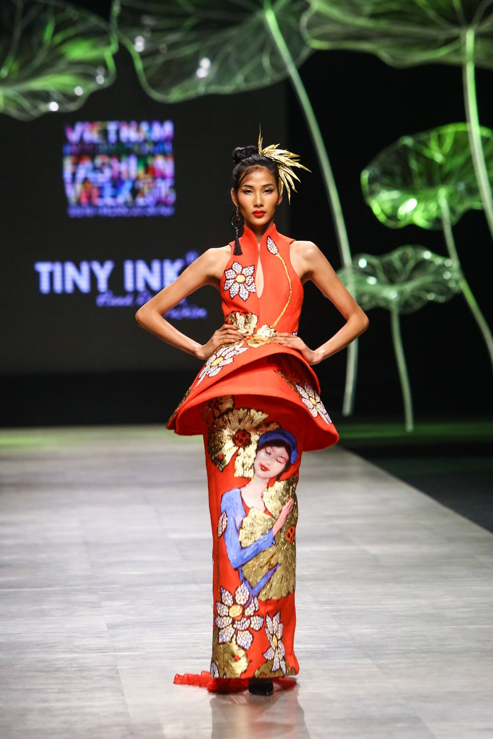 Tại sự kiện Vietnam International Fashion Week, tối 25/4, người mẫu  Hoàng Thùy diện váy dát vàng lên sàn diễn. Thiết kế mà Hoàng Thùy trình diễn được lấy ý tưởng từ chiếc nón lá Việt với các lớp xếp tầng tạo hiệu ứng đặc biệt trên thân áo. Đặc biệt, họa tiết hoa sen trên váy được dát bằng vàng thật khiến giới mộ điệu một phen bất ngờ.